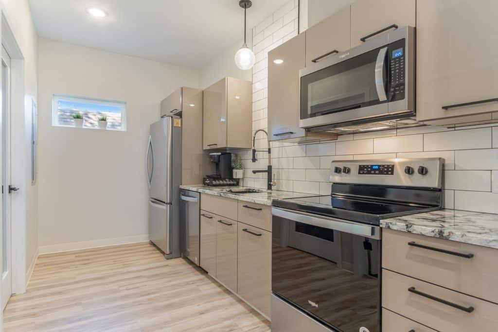 Bright modern kitchen with stainless steel appliances, granite countertops, and neutral cabinetry, perfect for West Michigan homebuyers seeking stylish and functional real estate options.