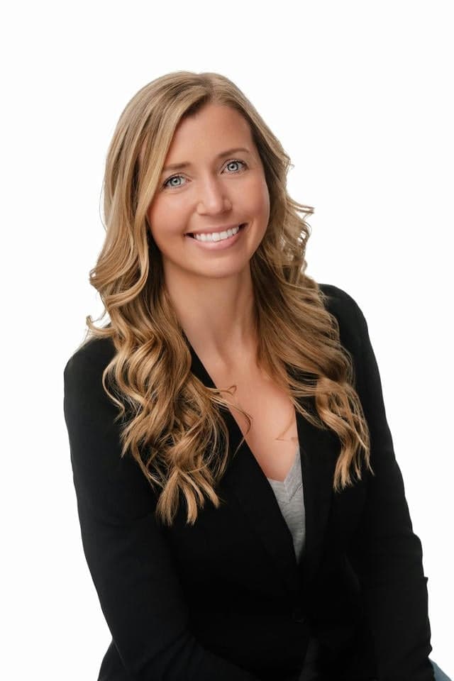 Beautiful female real estate agent smiling in professional attire, representing West Michigan real estate services.