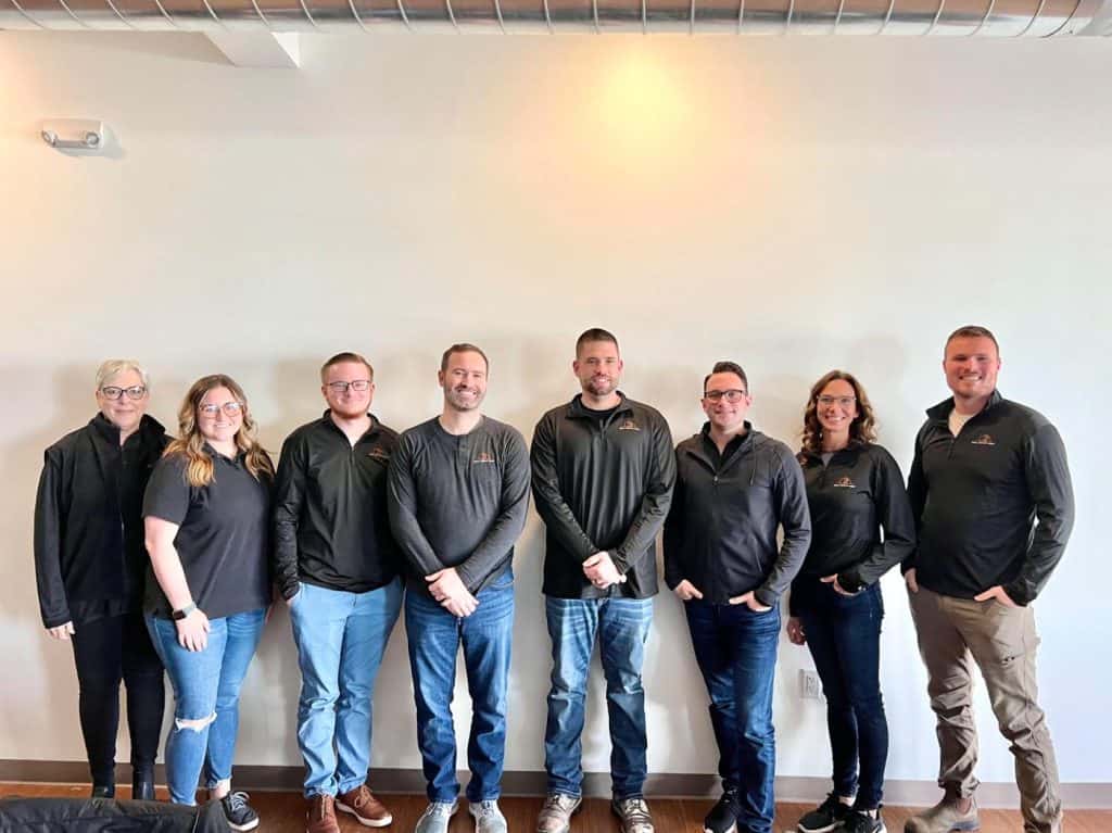 Team of real estate agents standing together in West Michigan, ready to assist with buying or selling homes. Expert realtors providing professional real estate services in West Michigan's housing market.