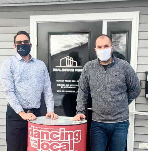 Real estate agents meeting outside a West Michigan property, promoting local homes and services.